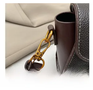 Détail d'un sac bandoulière en cuir marron foncé avec crochet doré et coutures précises