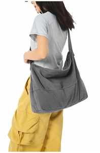 Détail d'un grand sac bandoulière en toile gris foncé montrant texture et bandoulière