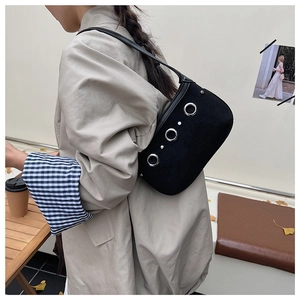 Gros plan du sac sous le bras en daim noir avec rivets argentés et œillets métalliques