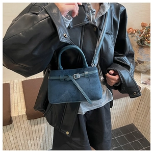 Detail der blauen Wildleder-Eimertasche mit Zierschnalle und Zylindergriff