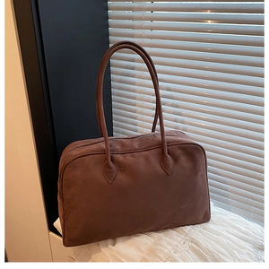 Macro detail of brown suede Boston bag showing high-quality stitching and textured finish