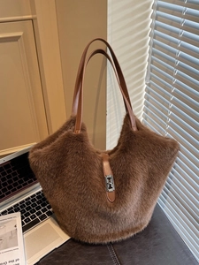 Brown fluffy faux fur tote bag with leather strap and metal clasp on an office desk