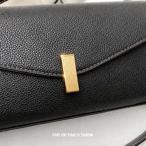 Detail of dark brown lychee leather bag with a striped gold metal rectangular lock
