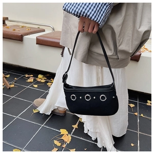 Détail du sac hobo en daim noir avec œillets métalliques argentés et rivets en automne