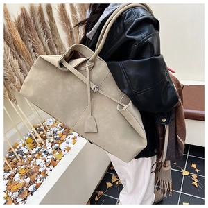 Detail of light beige suede tote bag with leather tassel on model in outdoor scene