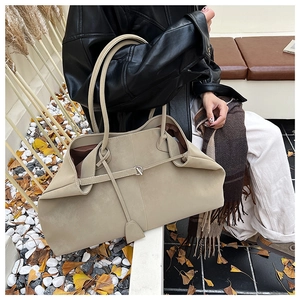Detail of beige suede tote bag featuring a decorative silver buckle and dark brown lining