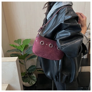 Détail du sac à bandoulière en daim bordeaux avec œillets métalliques et texture mate