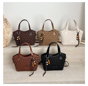 Quilted tote bags in multiple colors with bead tassels displayed on stone steps