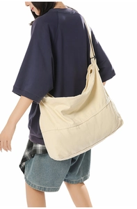 Vue latérale du grand sac bandoulière en toile blanc cassé porté avec style décontracté