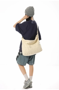 Détail du grand sac bandoulière en toile beige montrant la texture et la coupe ample