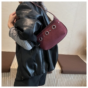 Détail du sac à bandoulière en daim bordeaux avec de grandes boucles en métal argenté