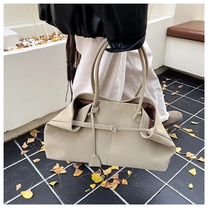Detail of soft beige leather tote bag with silver metal buckle and deep brown lining