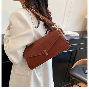 Détail d'un sac bandoulière en cuir grainé marron avec fermoir métallique rectangulaire