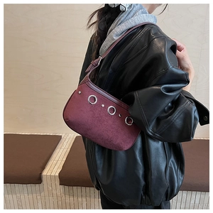 Gros plan sur le sac baguette en daim bordeaux avec anneaux argentés et rivets punk