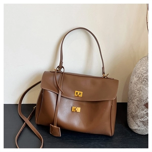 Detail view of brown leather bag featuring golden twist locks and adjustable shoulder strap