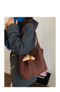 Vue détaillée du grand sac cabas en daim marron avec cordon et breloque en peluche