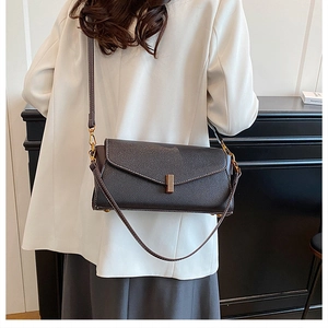 Détail d'un sac bandoulière en cuir noir grainé avec un fermoir en métal doré élégant