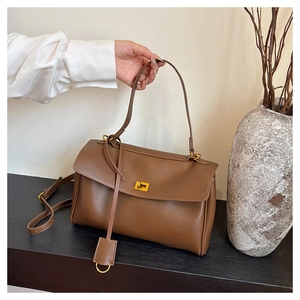 Close-up of brown leather bag with golden metallic twist lock on dark surface