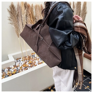 Detail of a large dark brown suede tote bag featuring adjustable side drawstring straps