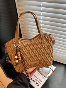 Chic brown woven bucket bag with stylish wooden bead pendant and adjustable shoulder strap
