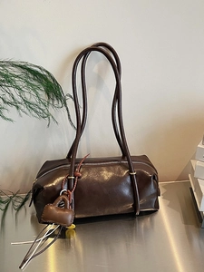 Minimalist large brown Boston shoulder bag with chic fringe pendant on a silver surface