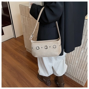 Vue détaillée du sac à bandoulière en daim beige avec anneaux métalliques et rivets argentés