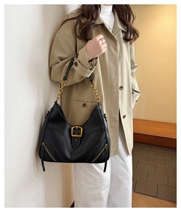Detailed view of black hobo bag with vintage gold buckle and chain strap on model