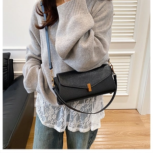 Détail du sac baguette en cuir grainé noir avec ferrures dorées et surpiqûres blanches
