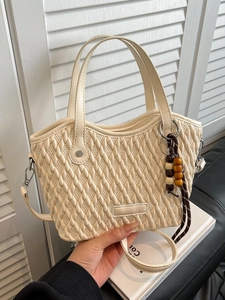 Cream quilted bucket bag with woven texture, dual handles and adjustable shoulder strap