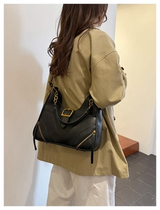 Detail of black vintage shoulder bag featuring gold buckle and chain accent on khaki coat