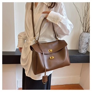 Brown soft leather underarm tote bag with gold twist locks worn by a model