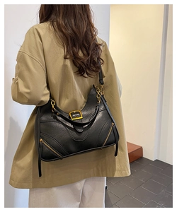 Detailed view of black vintage leather shoulder bag with gold square buckle and chain