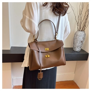 Brown leather tote bag featuring golden twist locks and a detachable shoulder strap detail