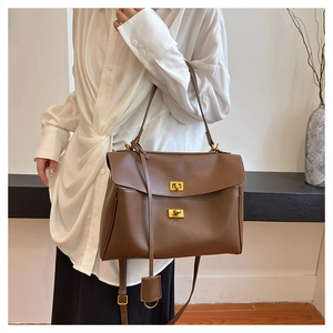 Detailed view of brown leather crossbody bag with gold twist lock and adjustable shoulder strap