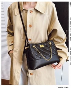 Close-up of black quilted PU leather tote bag featuring gold chain and turn-lock closure