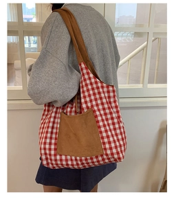 Sac fourre-tout à carreaux rouges et blancs avec bandoulière marron porté par un mannequin