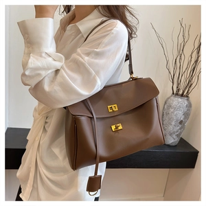 Detail of dark brown leather tote bag featuring elegant gold metal twist locks and hangtag