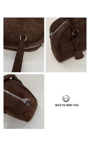 Detail view of dark brown suede Boston bag featuring silver zippers and metallic ring hardware