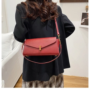 Détail du sac baguette en cuir grainé rouge avec boucle métallique dorée élégante