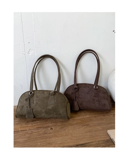 Detail of vintage suede shoulder bags in olive green and dark coffee on wooden stand