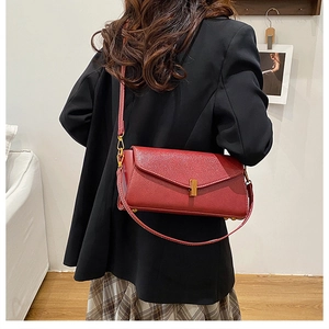 Détail du sac bandoulière en cuir rouge avec boucle en métal doré et texture grainée