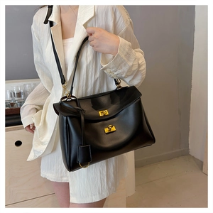 Detail of classic black shoulder bag with gold twist-lock buckle and smooth texture