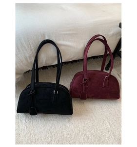 Minimalist matte suede pillow bags in black and burgundy on a soft white carpet