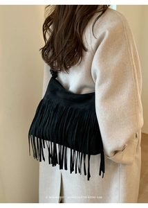 Détail du sac bandoulière en daim noir avec franges longues et sangle nouée sur modèle