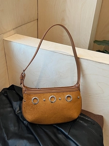 Sac sous le bras rétro en daim camel avec anneaux argentés et rivets sur fond de bois