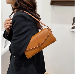 Détail d'un sac à bandoulière en cuir marron avec rabat asymétrique et boucle en métal