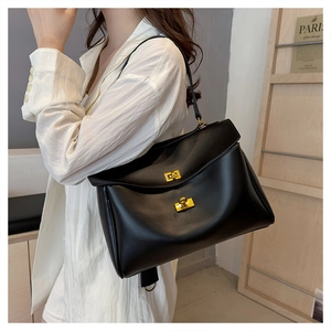 Close-up of minimalist black leather shoulder bag with elegant gold twist lock hardware