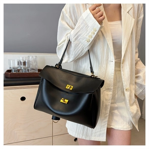 Model wearing a black soft leather underarm bag with gold metal turn-lock and handle