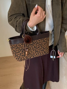 Leopard print faux suede tote bag with brown leather handles and pompom charm on model