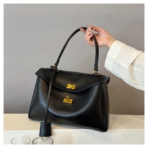 Detail of minimalist black matte leather tote with a gold square twist lock and padlock